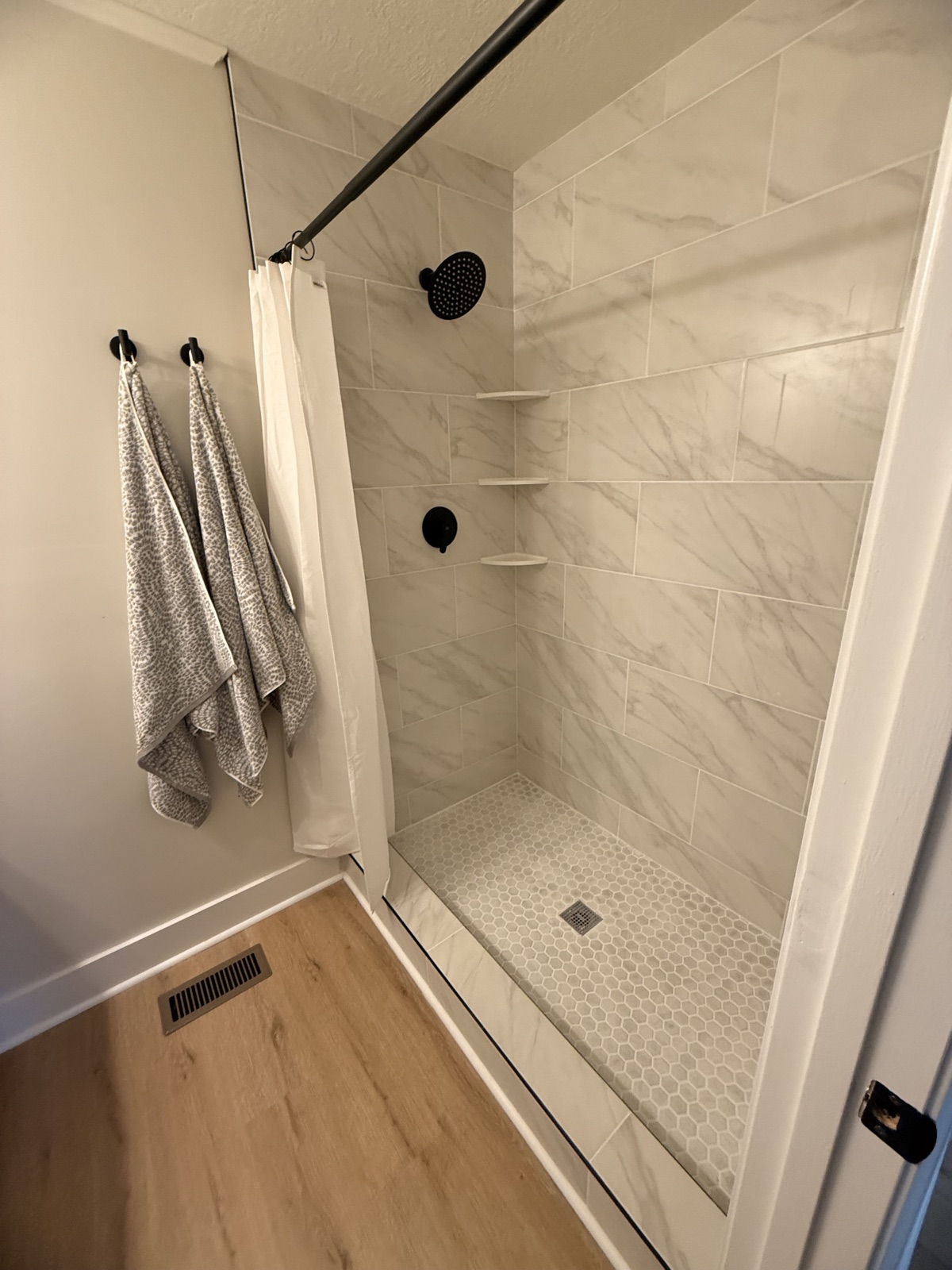 Marble tile walk-in shower with hexagon mosaic accent