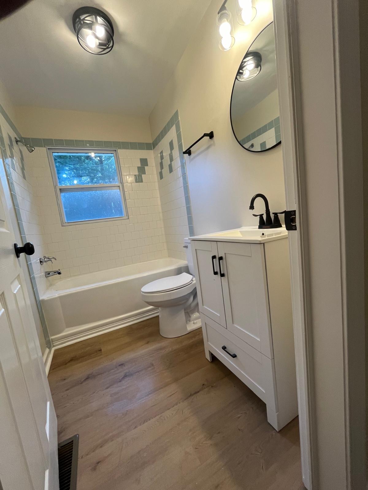 Subway tile bathtub surround with teal accent tiles