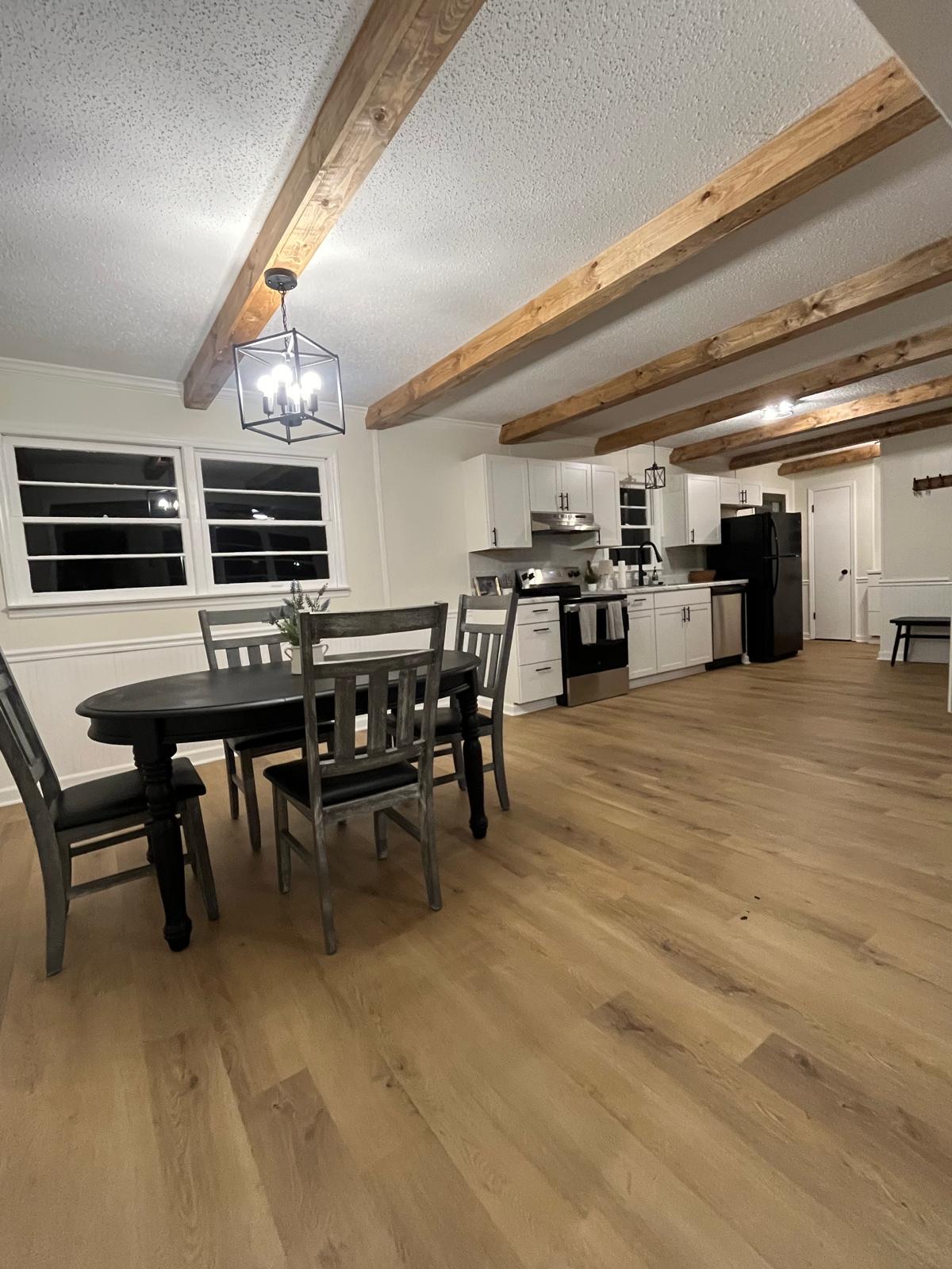 Open-concept kitchen and dining with exposed wood beams