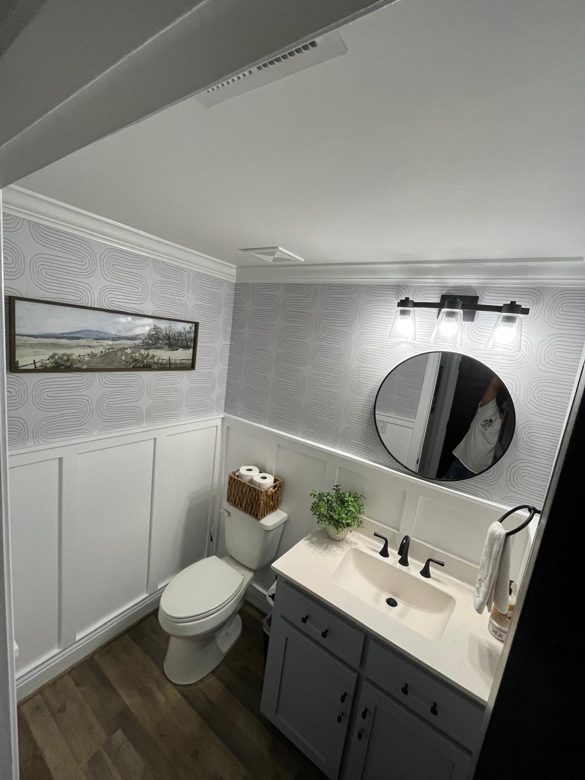 Powder room with patterned wallpaper accent wall and wainscoting