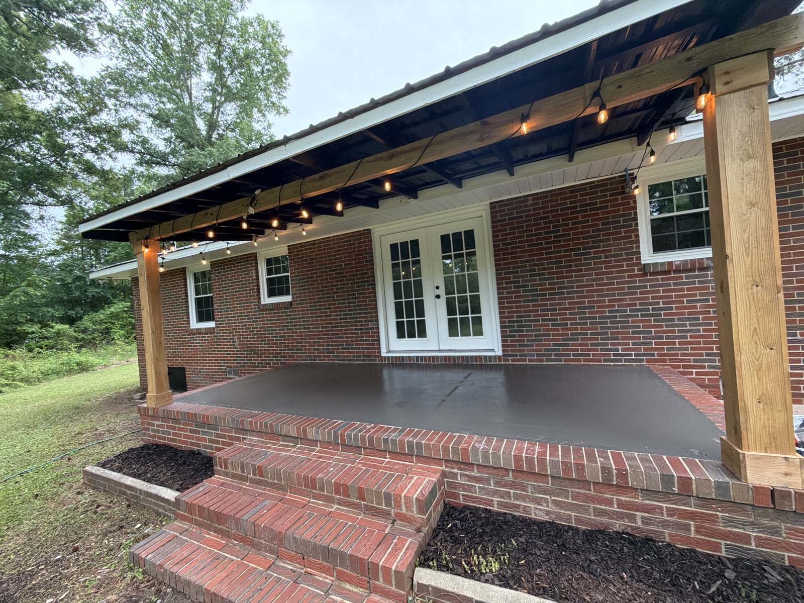 Covered back porch with poured concrete patio and string lights